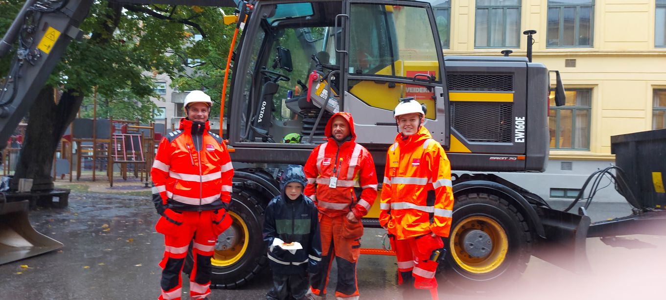 En gruppe mennesker i oransje jumpsuits som står foran en gul lastebil