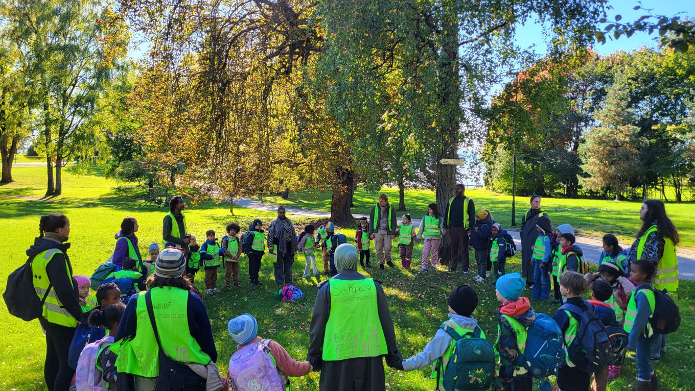 en gruppe mennesker som står i en park med trær og gress