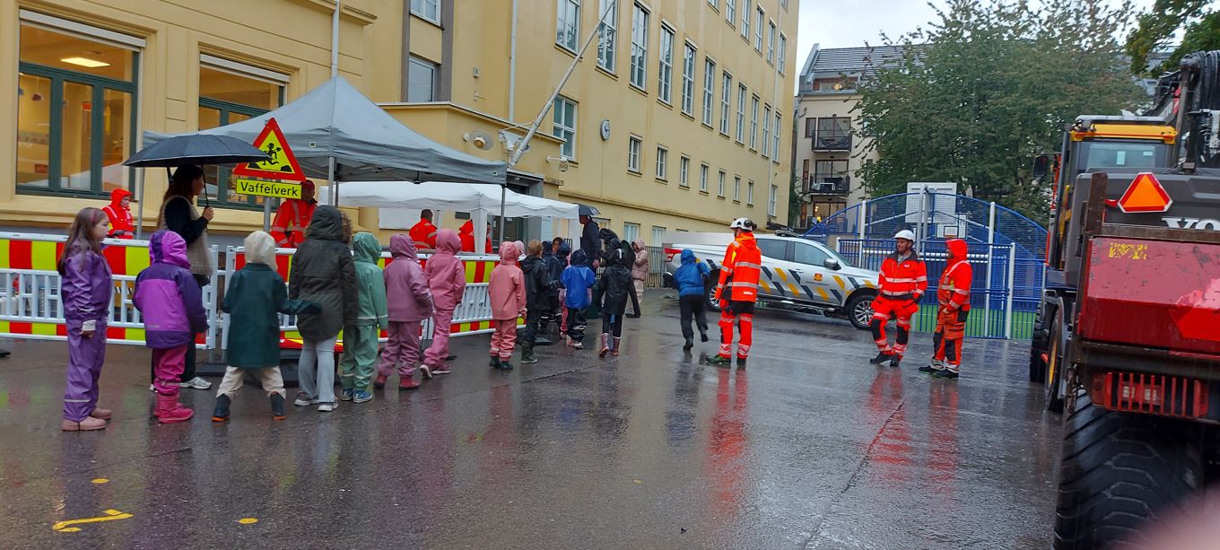 en gruppe mennesker som står på en gate med en brannbil og en bygning i bakgrunnen